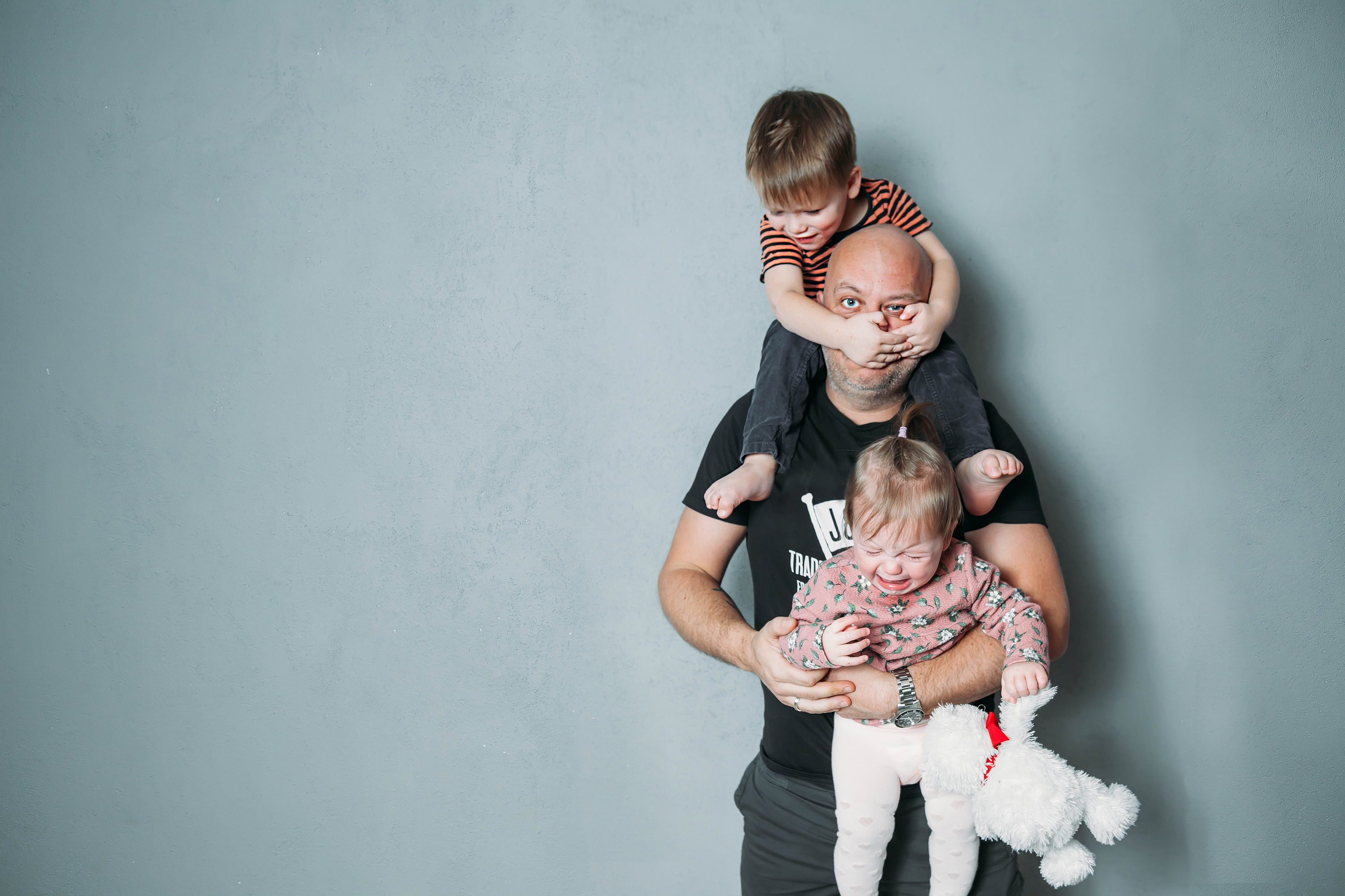 Dad with both a toddler sitting on his shoulders and a baby in his arms.