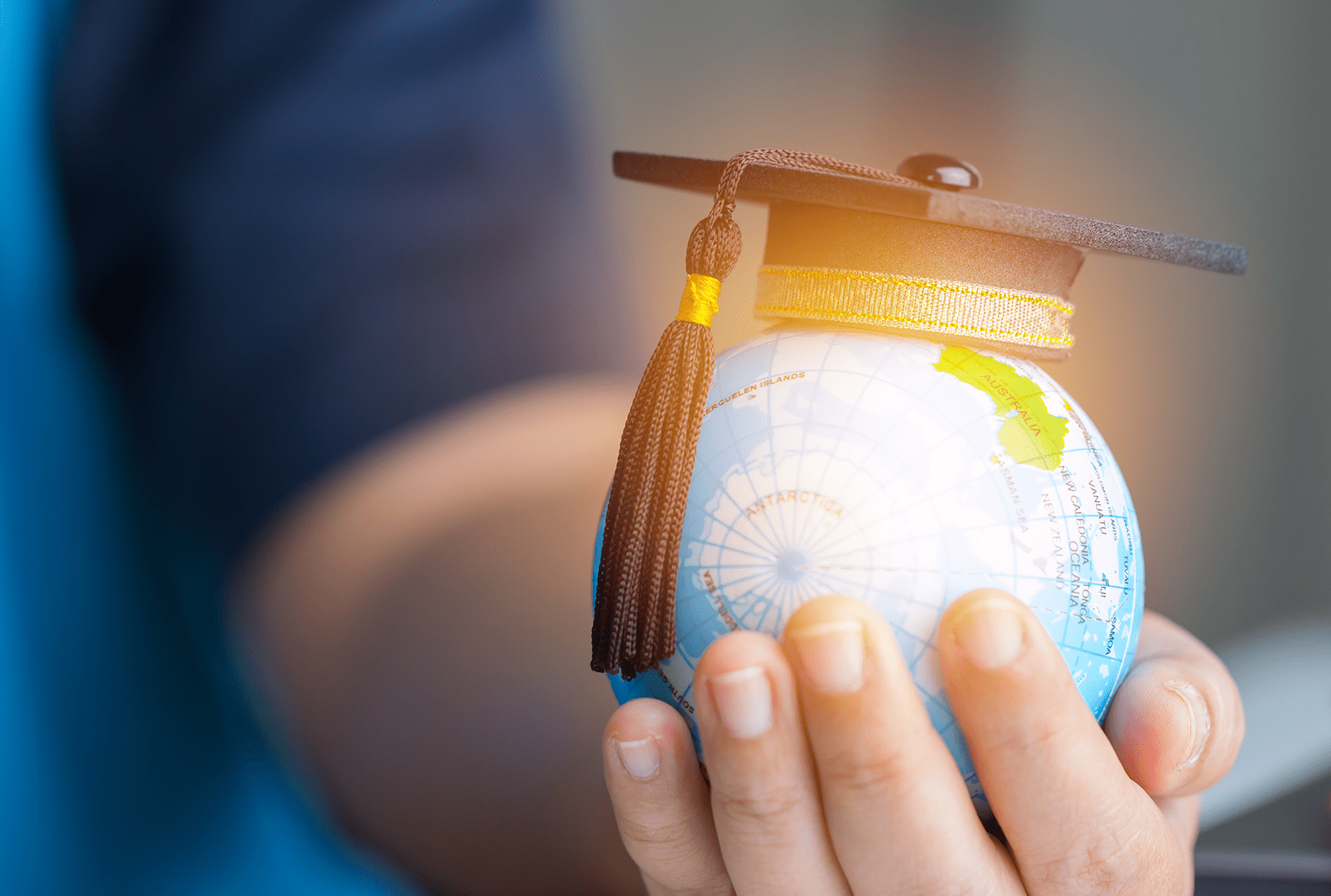 A child holds an orb of Earth, with a graduation cap on top.